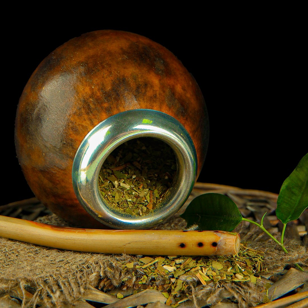 Cuia tradicional gaúcha com bomba e folhas de erva-mate ao redor — símbolo da herança da Mate Power